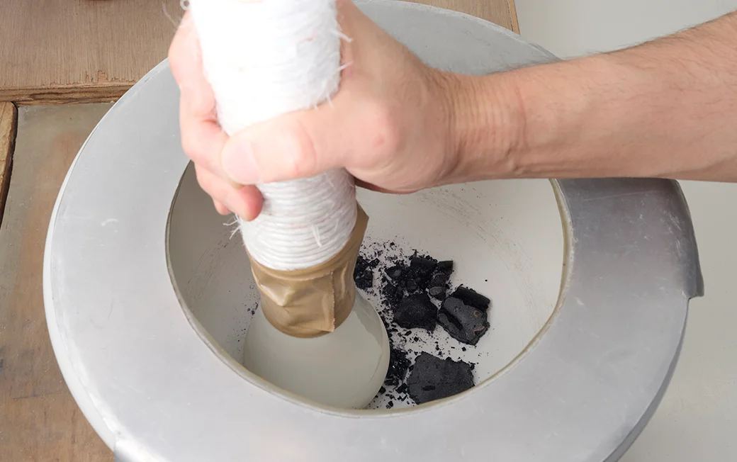 焼成後にできた塊を、再び手作業で粉末状にする画像